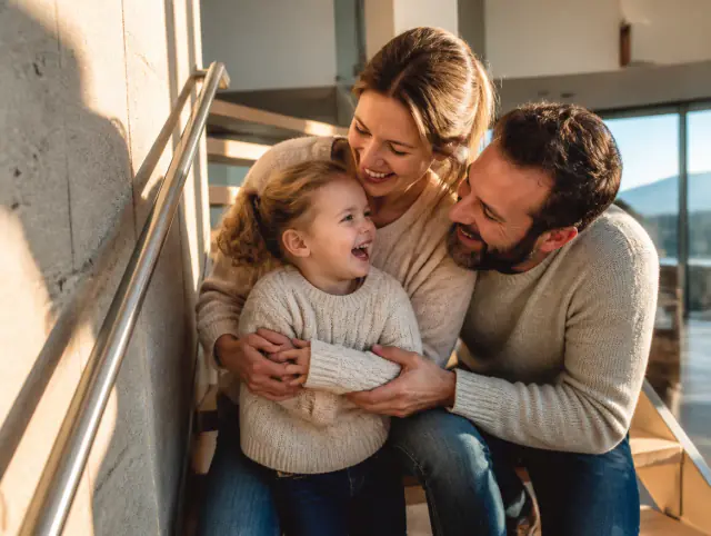 Glückliche Familie mit Kind lacht gemeinsam an einem Handlauf