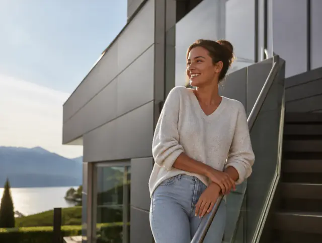 Handlauf für Aussentreppen – lächelnde Frau blickt zum Horizont Lächelnde Frau geniesst den Ausblick an einem Handlauf für Aussentreppen