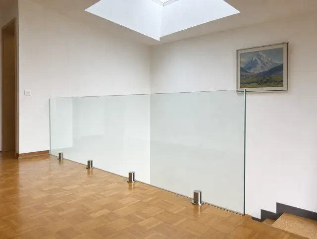 Rahmenlose Glasbrüstung ums Treppenauge im Zürcher Treppenhaus mit Eichenparkett